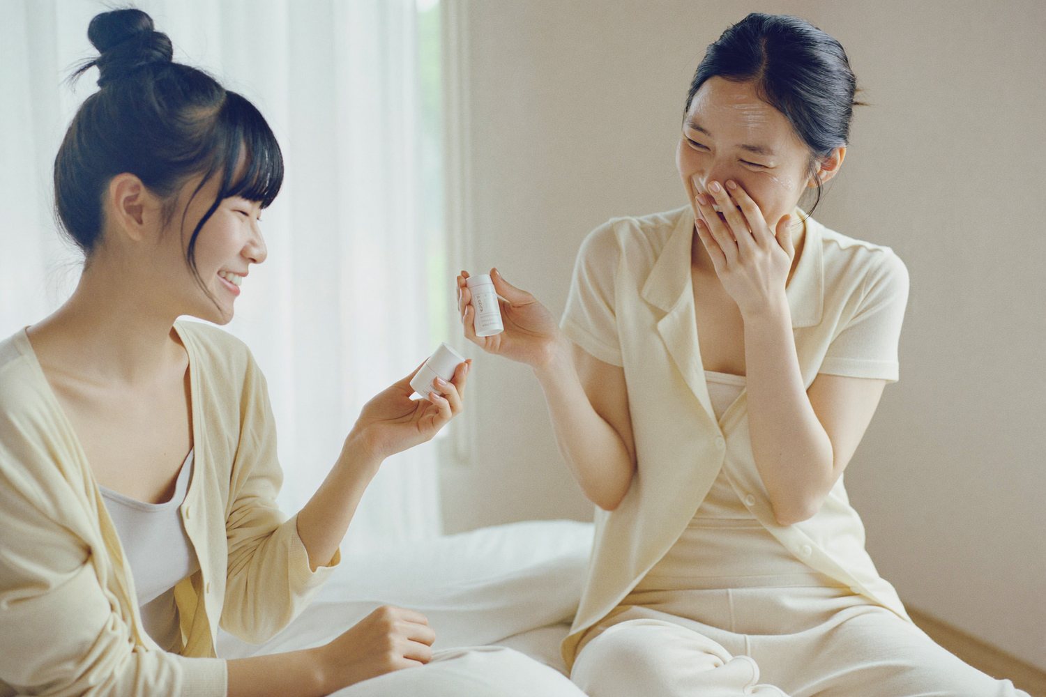 スキンケアをしながら笑い合う20代の女性ふたり